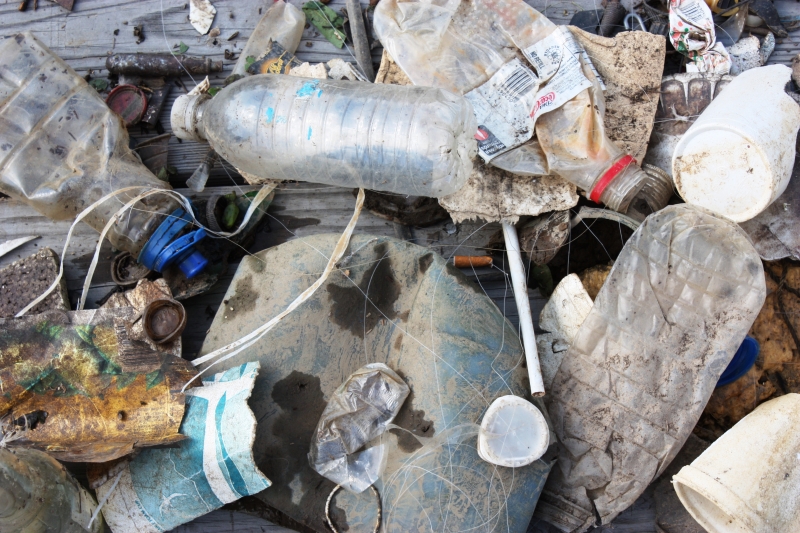 A pile of trash including plastic bottles, caps, and a straw.