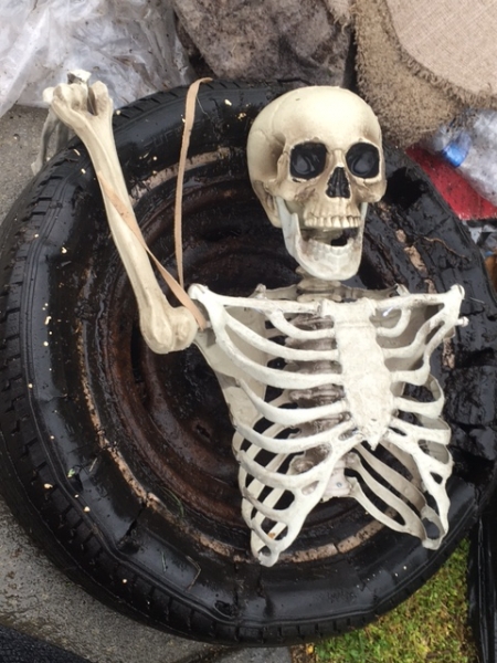 A Halloween skeleton decoration in a pile of trash.