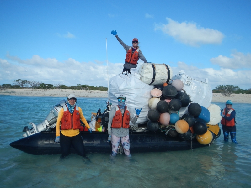 People in front of a boat filled with debris.