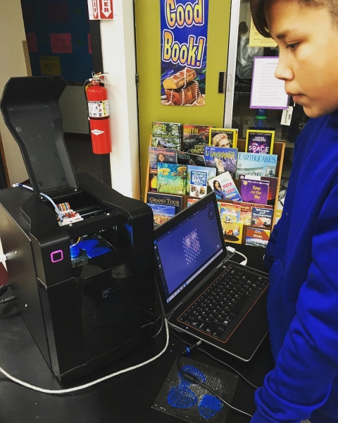 A boy standing in front of a 3D printer.