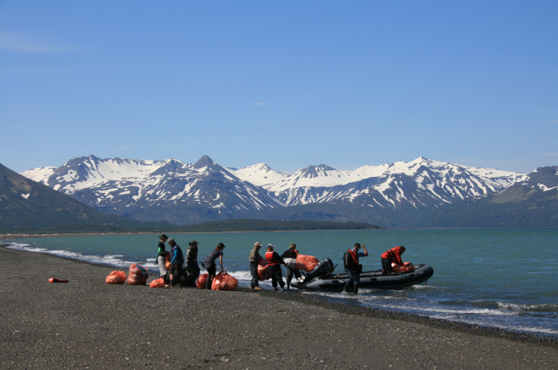 A group of people place bagged marine debris into a small boat.