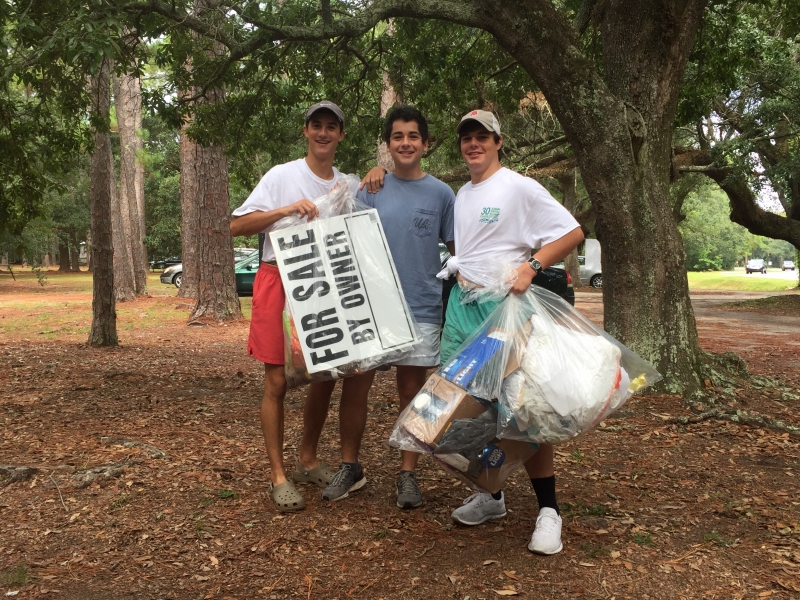 Three young men holding up trash