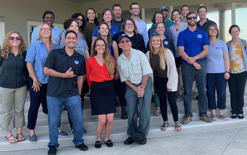 24 people stand on steps and smile for a picture.