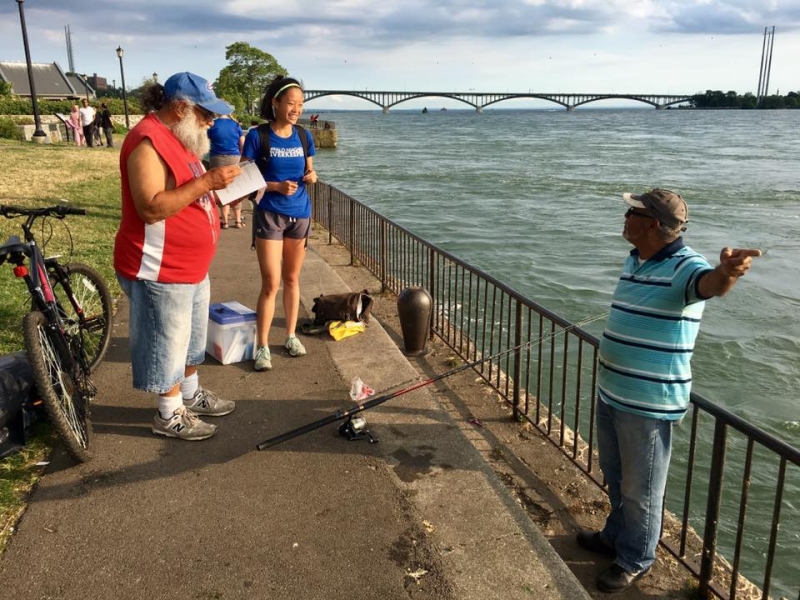 Three people stand on a fishing jetty having a conversation.