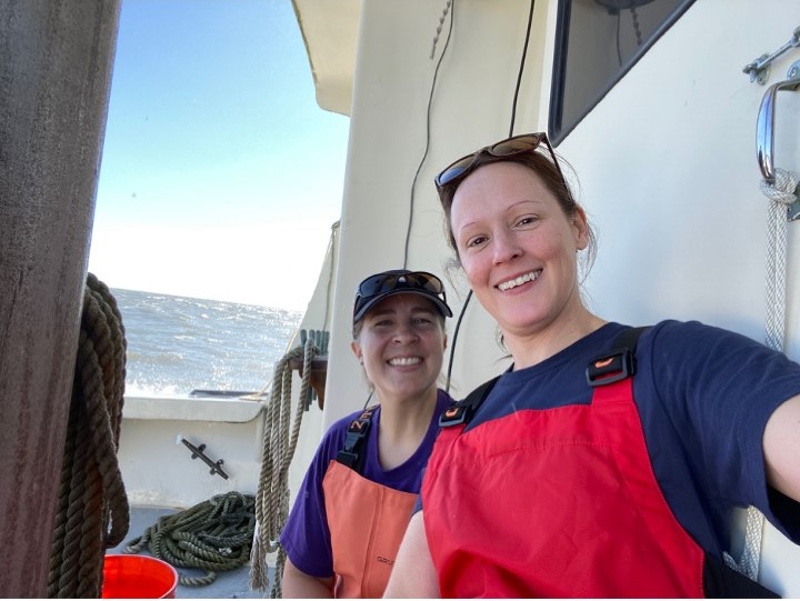 Two people smile for a picture while sitting on a boat.