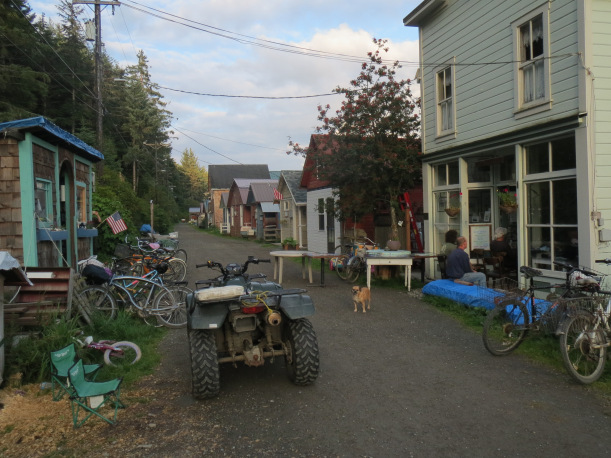 A trail runs between houses with an all terrain vehicle and several bikes.