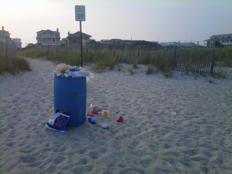 Overflowing trash can at the beach.