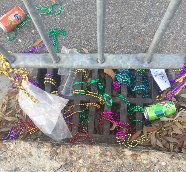 A gutter in Louisiana is tangled with aluminum cans and beaded necklaces.  