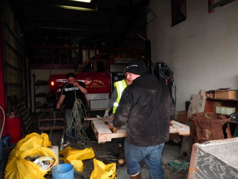 Men surrounded by piles of debris with a firetruck in the background. 
