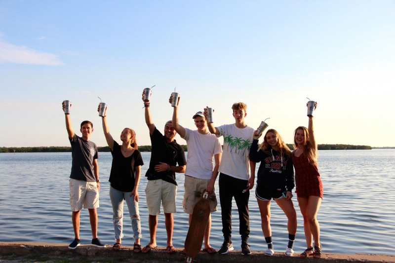 Students holding reusable cups on a beach.