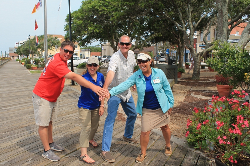 Four people reach out together for a group "high five".