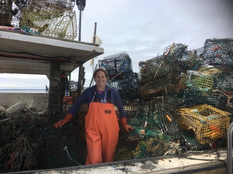 A woman poses with derelict traps on a boat.