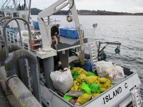 A boat with bags of debris on it.