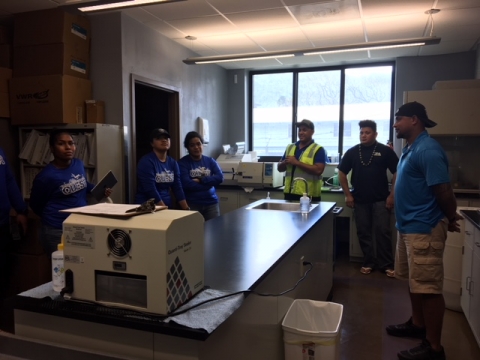 Six people stand around a table in a laboratory and smile for a picture.