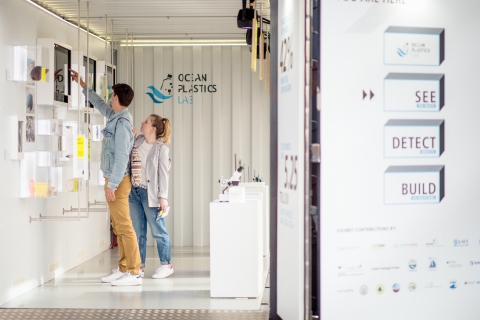 Two people looking at an exhibit on a wall.
