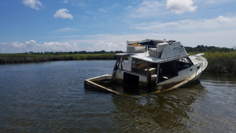 An abandoned and derelict vessel partially submerged in the water.