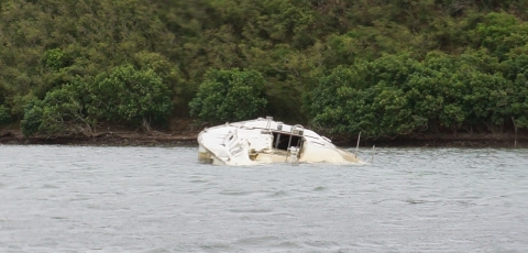 A derelict vessel partially-submerged in water.
