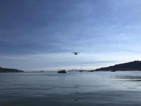 A seaplane begins to land on a smooth body of water.
