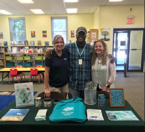 Three people smiling and standing behind a display table.