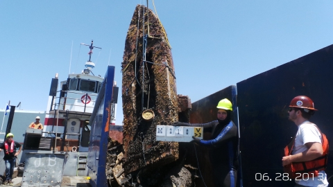 A derelict vessel pulled from the water with a crane.