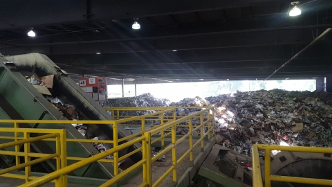 A large heap of trash and conveyor belt at a recycling center.