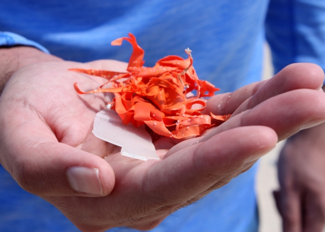 A cupped hand holding a piece of orange ribbon.