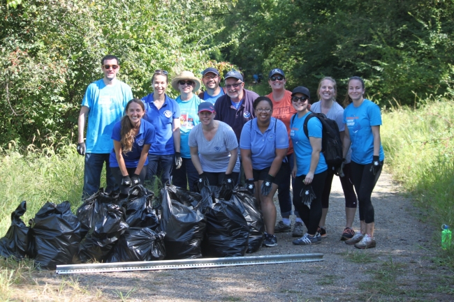 Several people stand behind full garbage bags of collected debris.
