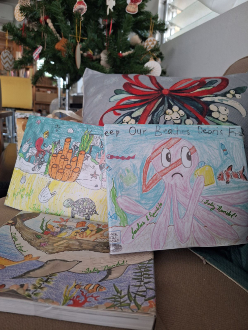 Books wrapped in artwork positioned underneath a Christmas tree.