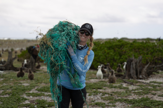 A person carries a net over their shoulder, smiling at the camera.