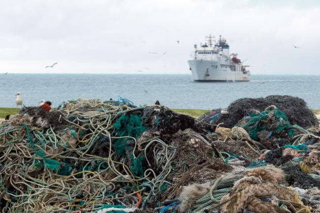 The marine debris pile with the NOAA ship Hi'ialakai in the background.
