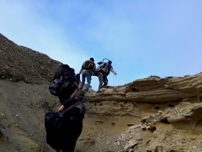 People hiking up a hill with backpacks on.