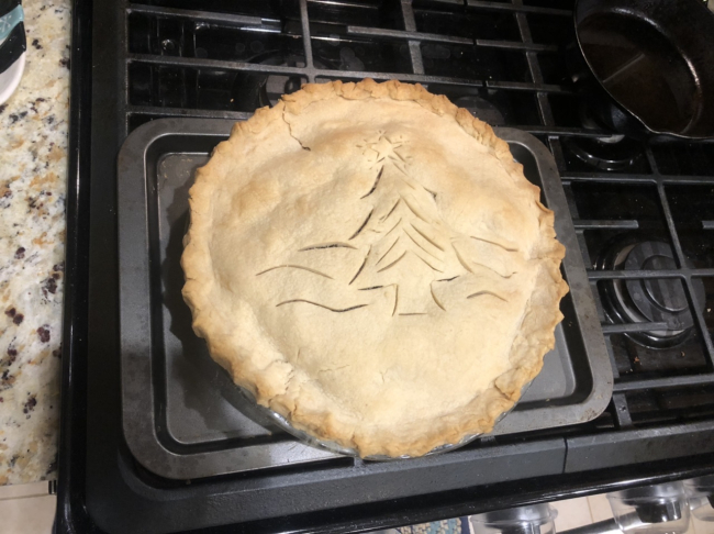 A pie fresh out of the oven with a Christmas tree design carved on the crust.