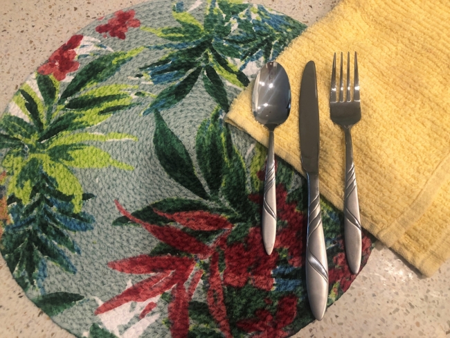 A placemat, utensils, and cloth napkin.