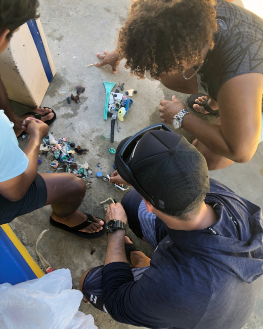 Three people sorting through a pile of marine debris they collected from a shoreline survey.