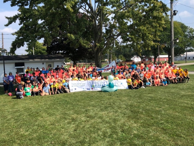 A large group of people smile together after a cleanup during the International Coastal Cleanup event.