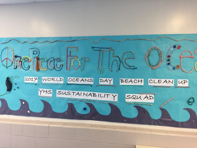 A bulletin board sign that says "One Piece for the Ocean."