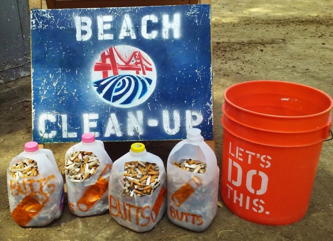 Four mile jugs and a 5 gallon bucket are full with cigarette butts.