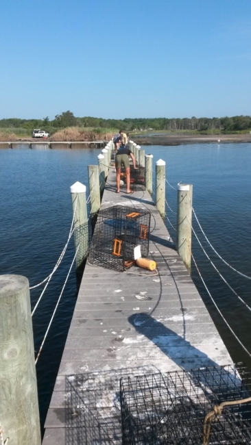 People work on a pier to stack crab pots.
