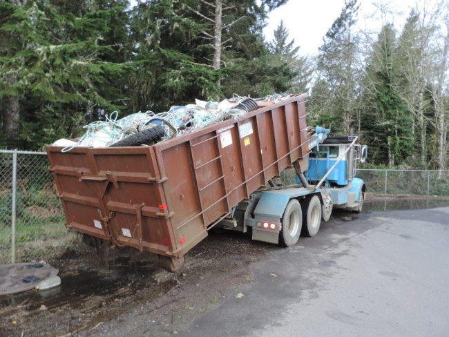 A dumpster full of debris being prepared to be hauled off.