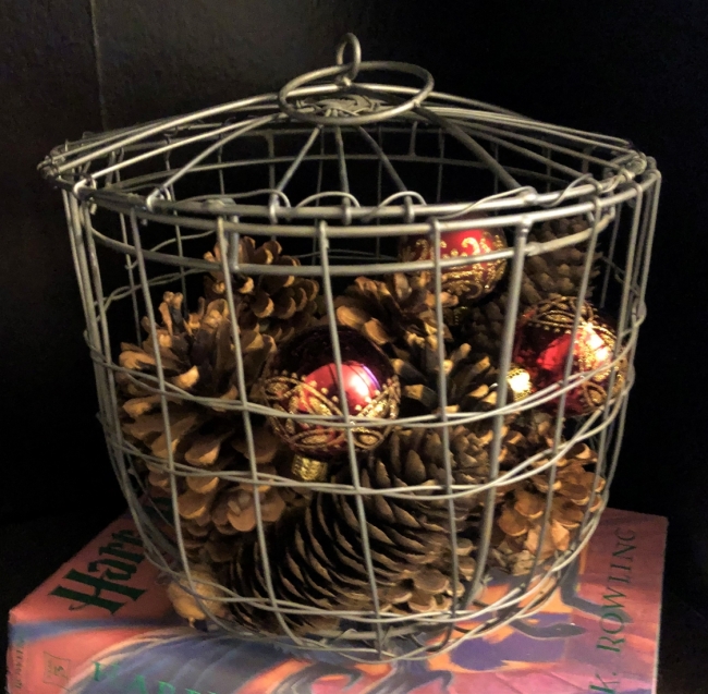 Several pinecones are contained inside a wire basket. 