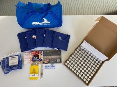 Contents of a kit, including a bag, t-shirts, collection jars, information cards, stickers, and a pad with pens.