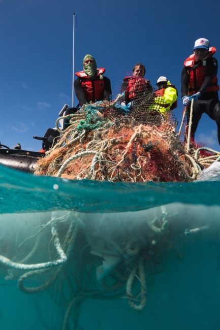 People haul a tangle of fishing nets into a boat at Pearl and Hermes Atoll.