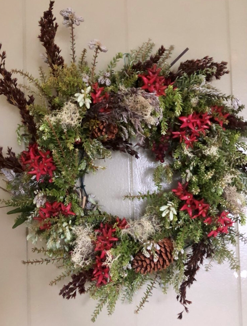 A wreath made of tree trimmings, flowers, and other natural materials. 