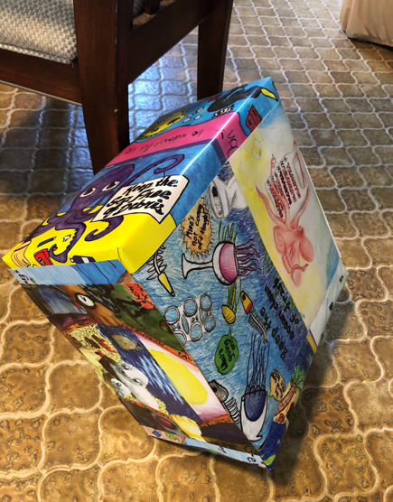 A gift wrapped in old calendar pages with artwork.