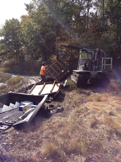 Volunteers using a machine to move large pieces of debris.