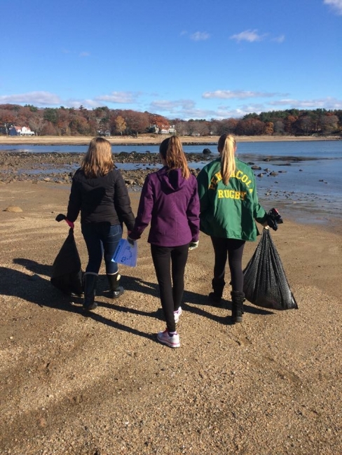 Students picking up trash on a beach.