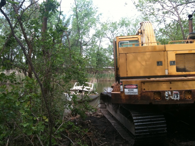 An excavator is brought in to remove a derelict vessel.