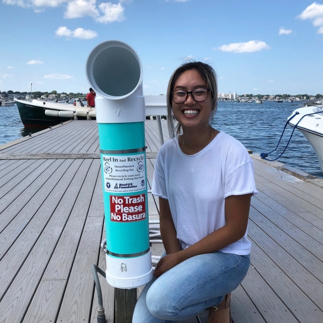A person poses with a bin on a dock.