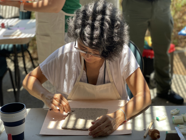 A woman leaning over a clay tile.