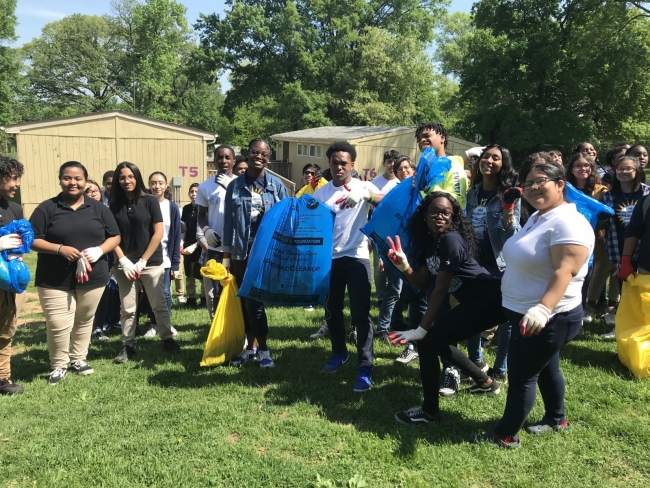 A group of students hold of bags of debris from a cleanup.